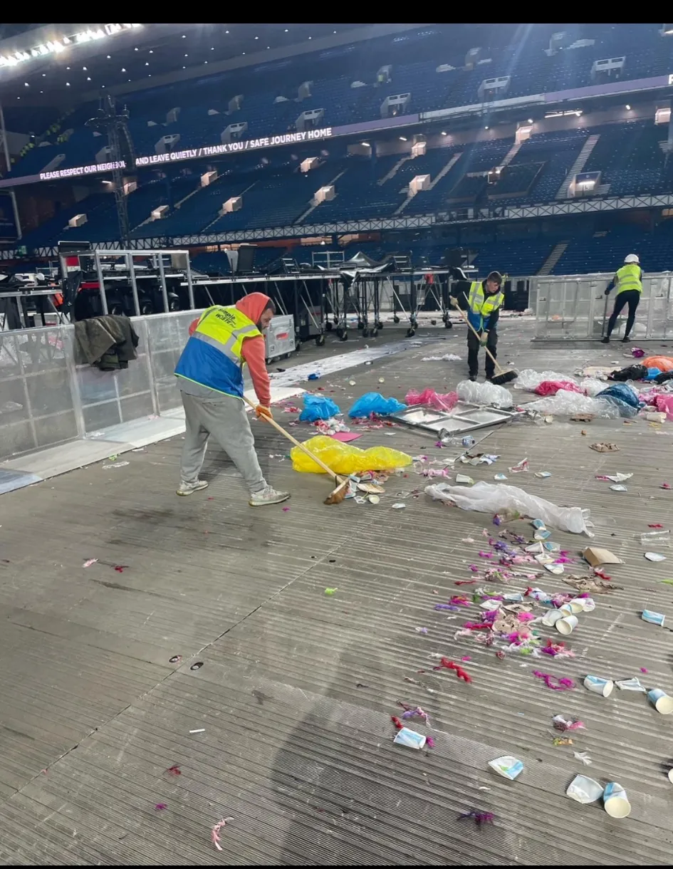 SWS operatives working across a large event floor clearing litter after a live event