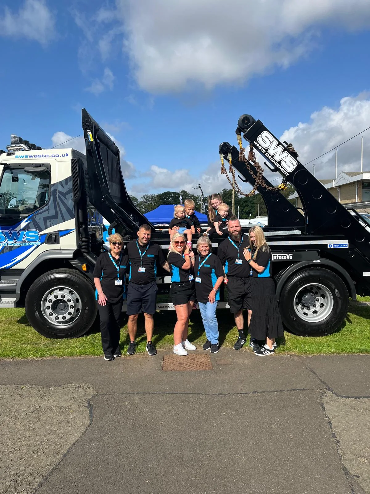 The SWS family together beside a blue and white SWS skip lorry
